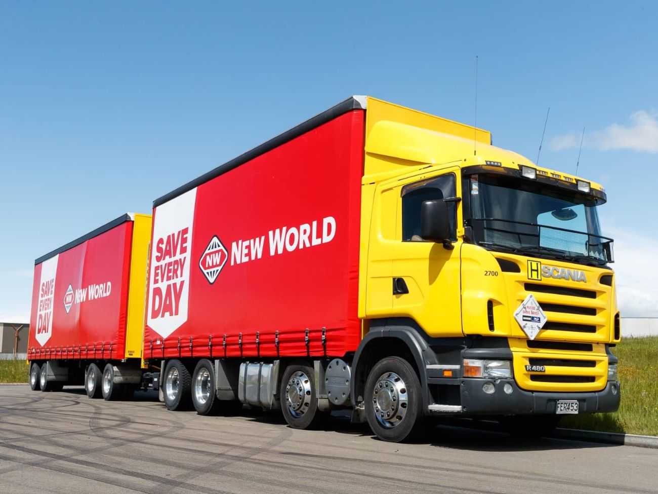 Red New World side curtains on a yellow truck and trailer.