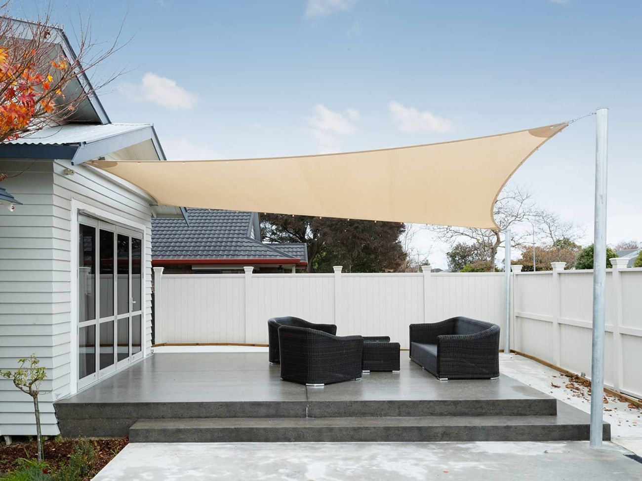 Cream shade sail with steel poles protecting a beautiful concrete outdoor area.